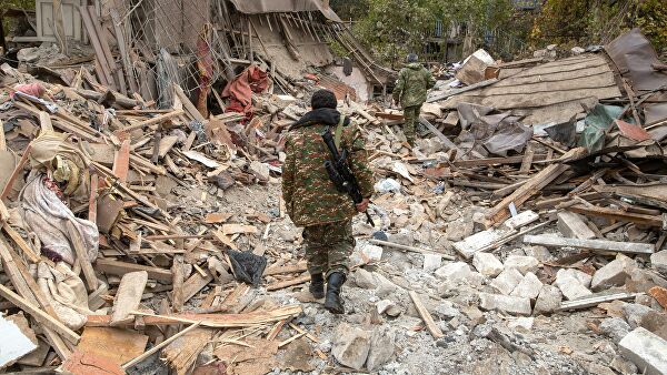 Вооруженные люди возле дома, поврежденного в результате обстрела Степанакерта