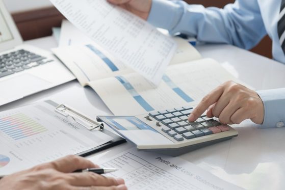 Someone using a calculator, surrounded by paper