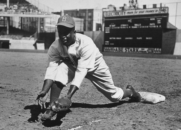 Jackie Robinson grounds ball at first base, 1950s.