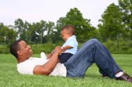 A father and his little son playing on grass.