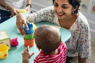 Image of South Asian teacher with child in a classroom.