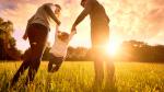 Parents playing with their young daughter in the evening sun