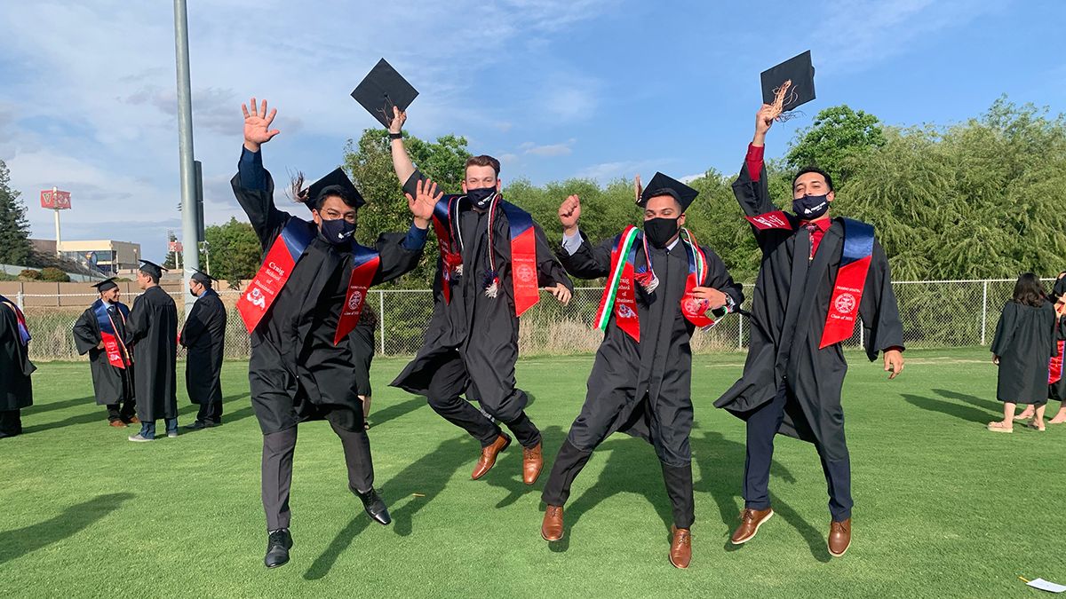 A group of people wearing graduation caps and gowns and holding diplomas while humping in the air.