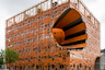 В 2011 году ярким пятном дополнился облик Лиона — архитекторы из французского бюро Jakob + MacFarlane построили в портовой части города офисное здание в форме куба с гигантскими пустотами. Экспериментальный проект должен был улучшить пейзаж района, где раньше располагались склады. Архитекторы <a href="https://www.archdaily.com/111341/the-orange-cube-jakob-macfarlane-architects" target="_blank">установили</a> на фасаде каркас с пиксельным узором, благодаря которому внутрь проникает солнечный свет. В качестве главного цвета использовали яркий оранжевый. Естественное освещение поступает в куб и через огромные отверстия на входе, на углу фасада и на крыше. Из-за необычного дизайна постройка <a href="https://www.20minutes.fr/lyon/406000-20100521-ovni-orange-derange" target="_blank">вызвала</a> у местных жителей ассоциацию с куском сыра.