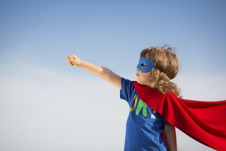 Young boy in red superhero cape and mask.