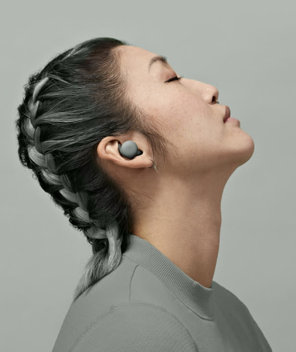 A young woman with her eyes closed and head slightly tilted back is immersed in the audio coming from her Pixel Buds A-Series.