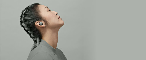 A young woman with her eyes closed and head slightly tilted back is immersed in the audio coming from her Pixel Buds A-Series.