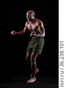 Side view of a black man with fists clenched and shouting on a black background. Стоковое фото, фотограф Iván Moreno / Фотобанк Лори