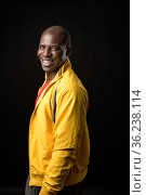 Side view of an African American man standing looking at camera and smiling. Стоковое фото, фотограф Iván Moreno / Фотобанк Лори