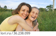 Senior mother with gray hair with her adult daughter in the garden hugging each other during picnic during sunny day outdoors, mothers day. Стоковое видео, видеограф Ольга Балынская / Фотобанк Лори