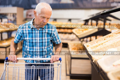 elderly man buying bread and pastries in grocery section of the supermarket