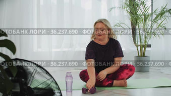 Blonde overweight woman doing fitness exercises with dumbbells then drinks water from the bottle