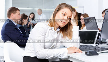 Portrait of unhappy girl in modern open plan office on background with coworkers