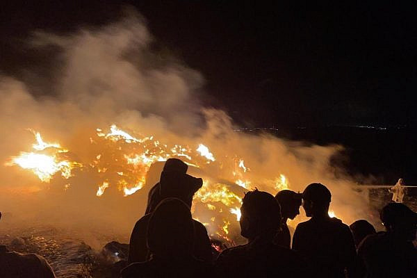 Palestinians in the village of Tuba in the South Hebron Hills look on after settlers set fire to their hay bales, June 1, 2021. (Courtesy of Jaber Awad)