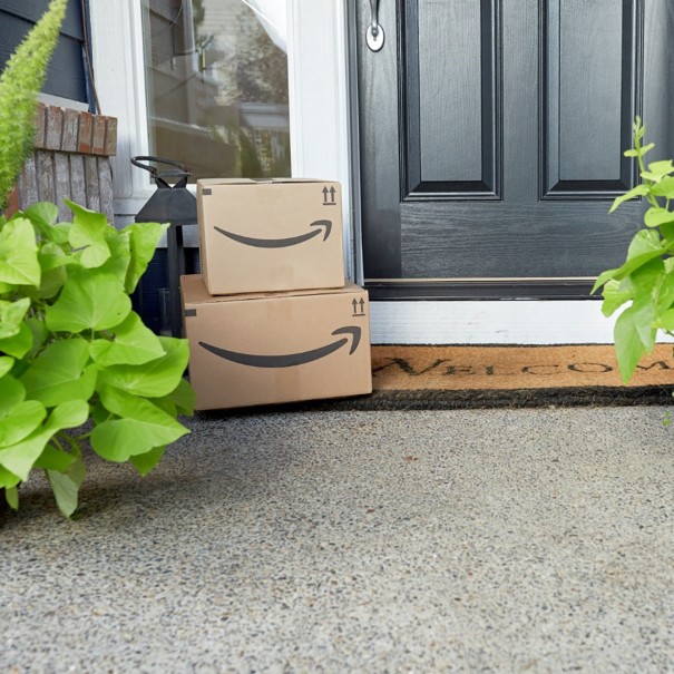 Two Amazon packages stacked on a door mat on a front step. 