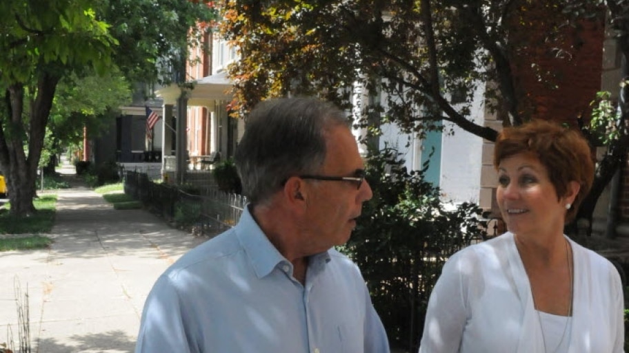 a man and woman holding hands walk down a city sidewalk. 