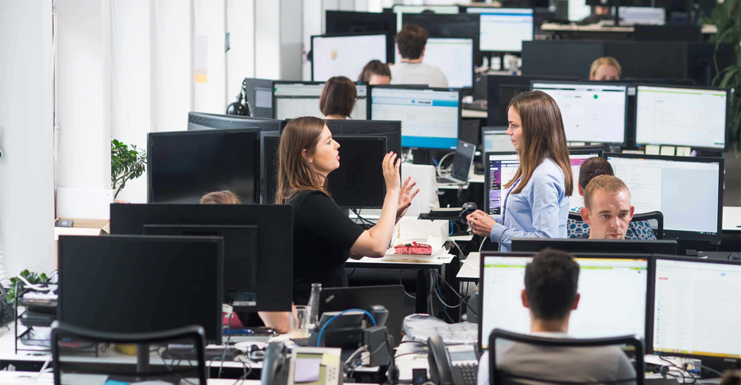 Une photographie de deux employés engagés dans une conversation dans les bureaux de Trustpilot.