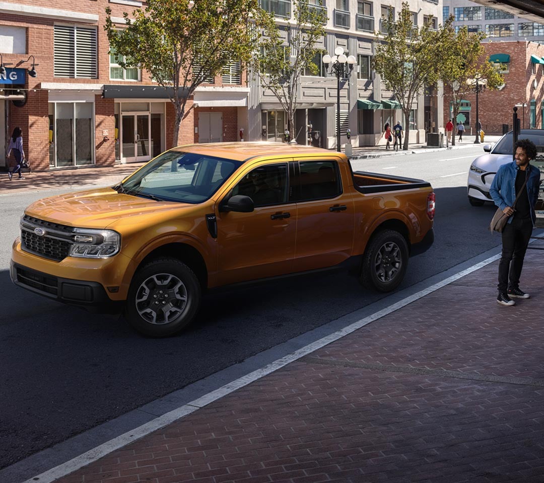 2022 Ford® Maverick XLT in Cyber Orange with rear view camera parallel parking outside a café