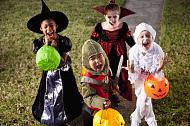 Four children wearing costumes with pumpkin trick or treat buckets in their hands.