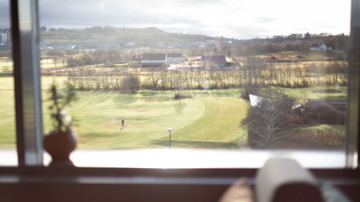 Golfplatz im Sonnenschein, fotografiert durch einen große Festerfront.