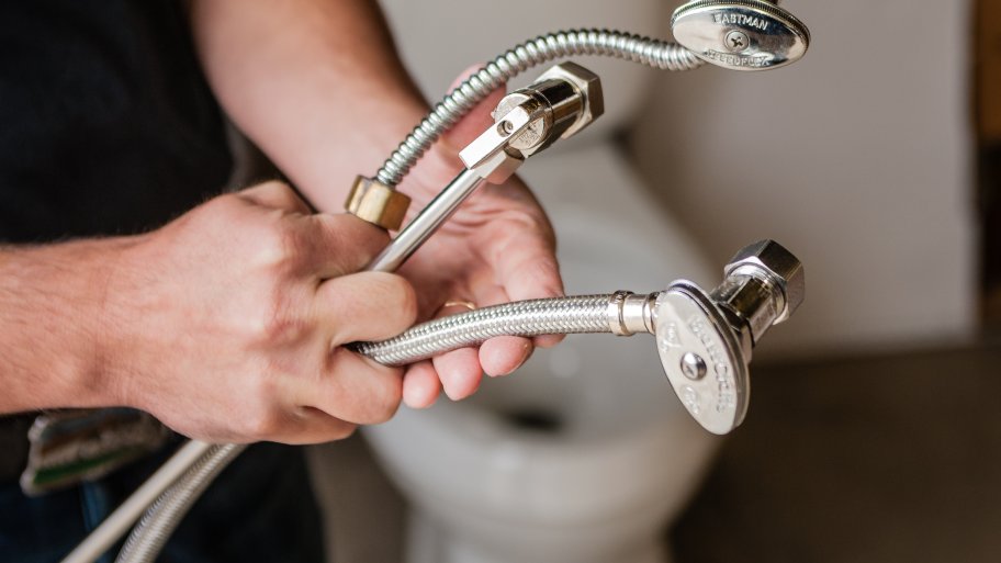 plumber holding supply lines and valves