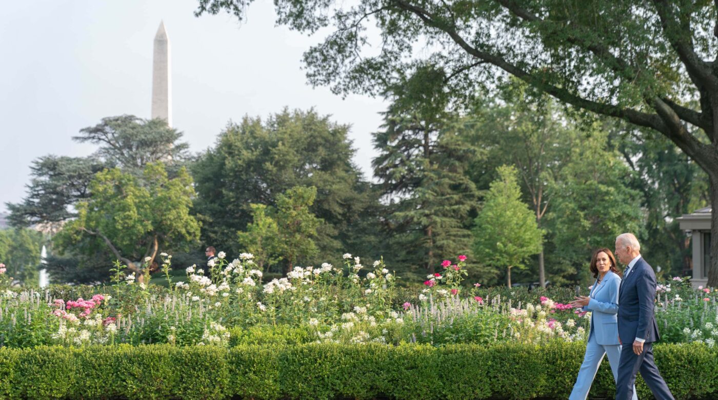 President Joe Biden and Vice President Kamala Harris walk in front of a garden at the White House.