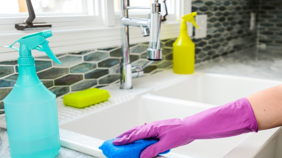 cleaning kitchen sink in purple gloves