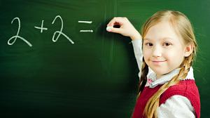 a young girl doing a simple calculation on a blackboard smiling at the fotographer.