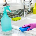 cleaning kitchen sink in purple gloves