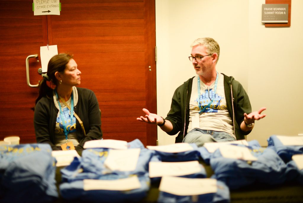 Two Volunteers sit at the t-shirt station