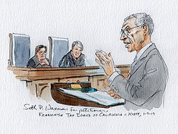 A man speaking at a lectern before two supreme court justices.