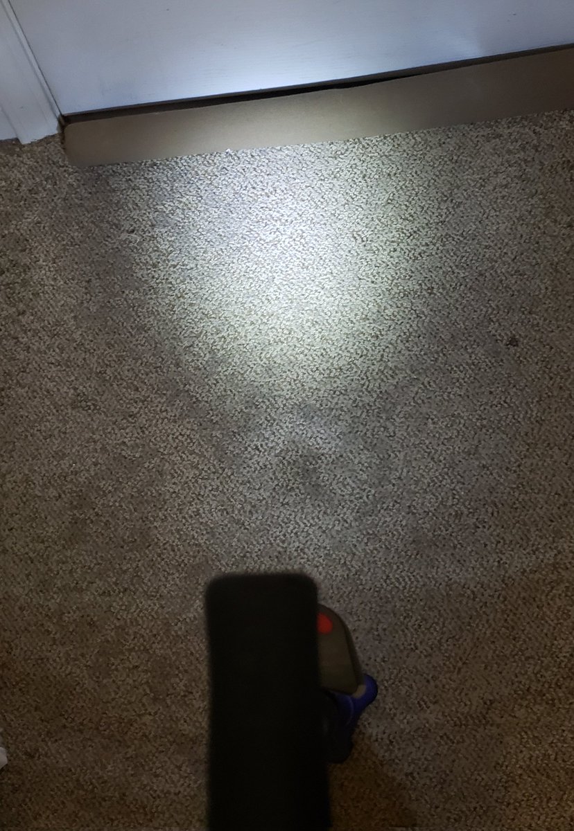 Beige carpet being illuminated by the PathLight attached to the cane that is pictured from above.