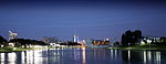 A large river flows through a brightly lit city at night.