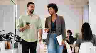 A man and woman walk down the hall of an office.