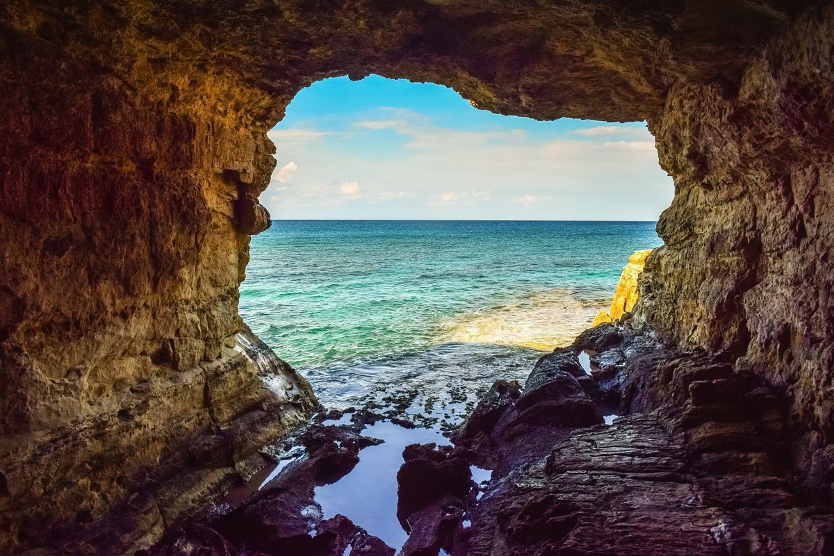 Photo of a cave leading out into a body of water that is probably an ocean