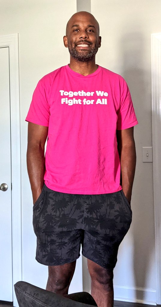 A Black man in a pink shirt that says "together we fight for all"