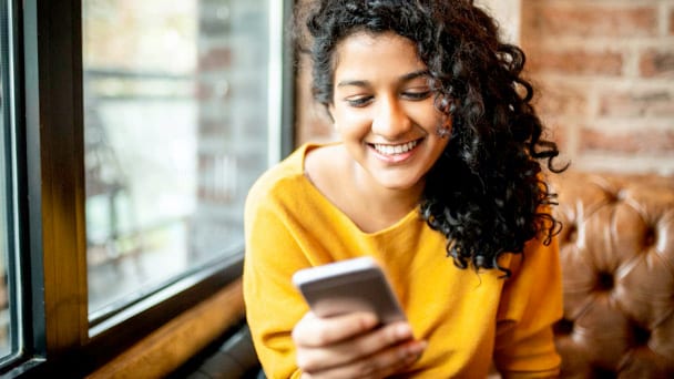 Mujer sonriendo con un teléfono móvil en la mano