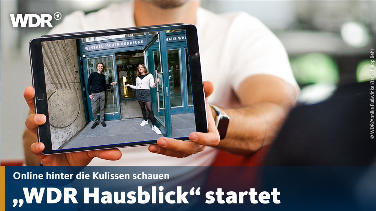 Ein Mann hält ein Tablet, auf dem zwei Personen in den WDR einladen. Dazu der Text: "Online hinter die Kulissen schauen. 'WDR Hausblick' startet"