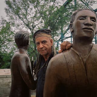 The artist Jerome Meadows stands behind his bronze statue of Ed Johnson, a Black man who was lynched from Chattanooga’s Walnut Street Bridge in 1906.
