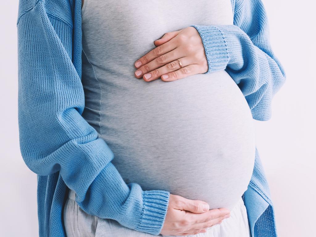 Young pregnant woman in medical mask hugging belly. Concept protection and prevention during viruses, mother care of her and  unborn baby health. Pregnancy and childbirth during infectious diseases.