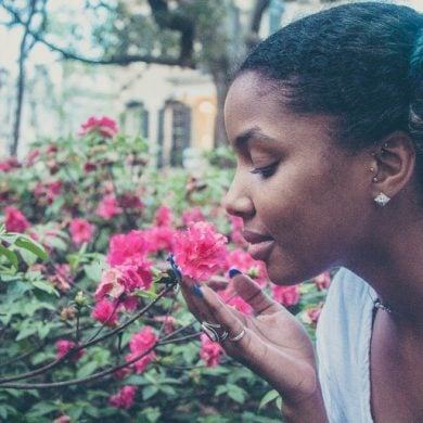 This shows a woman smelling flowers in a garden