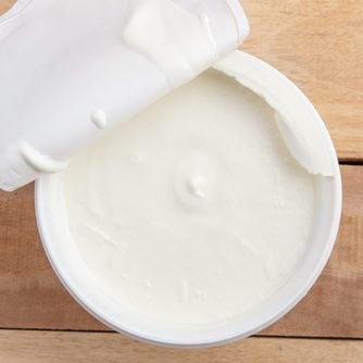 open container of greek yogurt on wood table