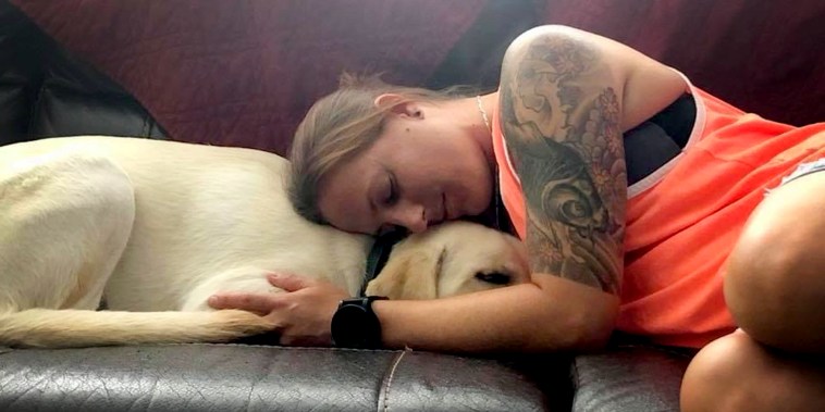 Becca Stephens comforting her service dog Bobbi on the couch in Clearwater, FL.