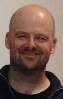 A bald middle-aged man smiling at the camera.