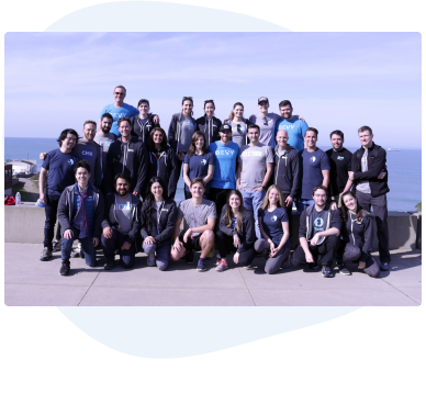 27 people standing in front of an ocean background, wearing Bevy t-shirts