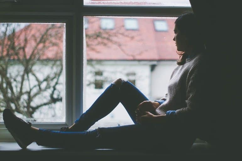 This shows a depressed looking woman sitting by a window