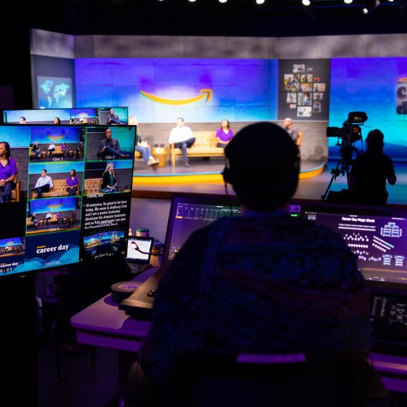 A person sitting behind a series of monitors works on Amazon Career day