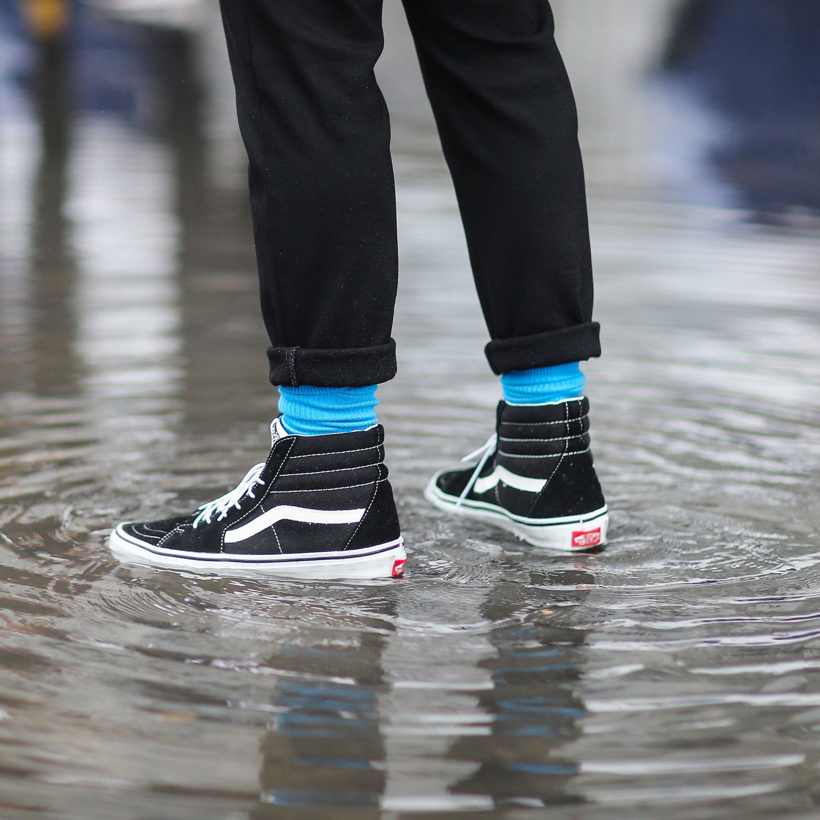 PARIS FRANCE  MARCH 01  A photographer wears blue socks black sneakers shoes and is standing in a water puddle outside...