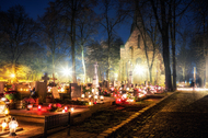 A churchyard at night lit up by burning candles on the graves.