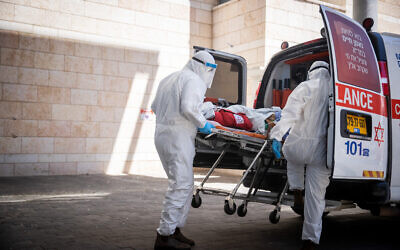 Magen David Adom workers wearing protective clothing evacuate a patient suspected of carrying the virus that causes COVID, at Hadassah Hospital Ein Karem in Jerusalem on August 15, 2021. (Yonatan Sindel/Flash90)